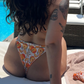 close up on backside of woman wearing a reversible orange / orange print high hip thong bikini bottoms