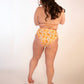 backside of woman in orange print triangle bikini top and high hip high waisted mid coverage bikini bottoms