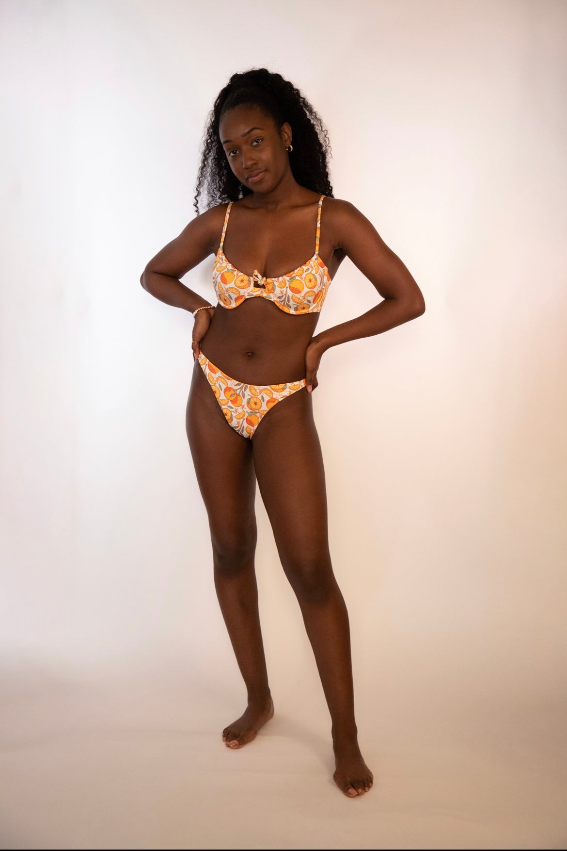 woman wearing a reversible orange / orange print high hip thong bikini bottoms and matching underwire bikini top