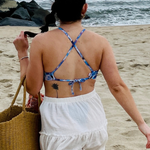 woman on the beach in a white skirt and a cross back blue floral bikini top