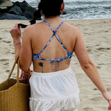 woman on the beach in a white skirt and a cross back blue floral bikini top