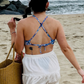 woman on the beach in a white skirt and a cross back blue floral bikini top