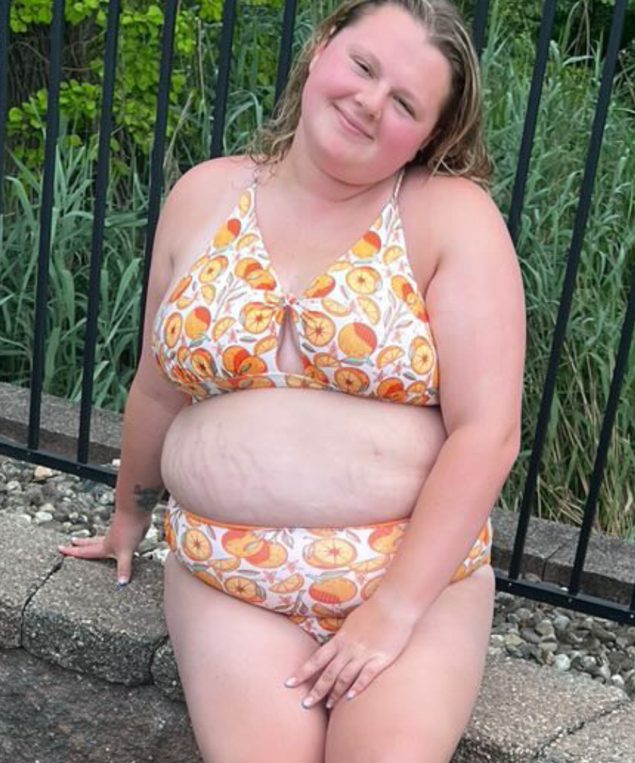 plus sized woman in supportive orange print peek a boo, crossed back top and matching high waisted bottoms