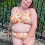 plus sized woman in supportive orange print peek a boo, crossed back top and matching high waisted bottoms