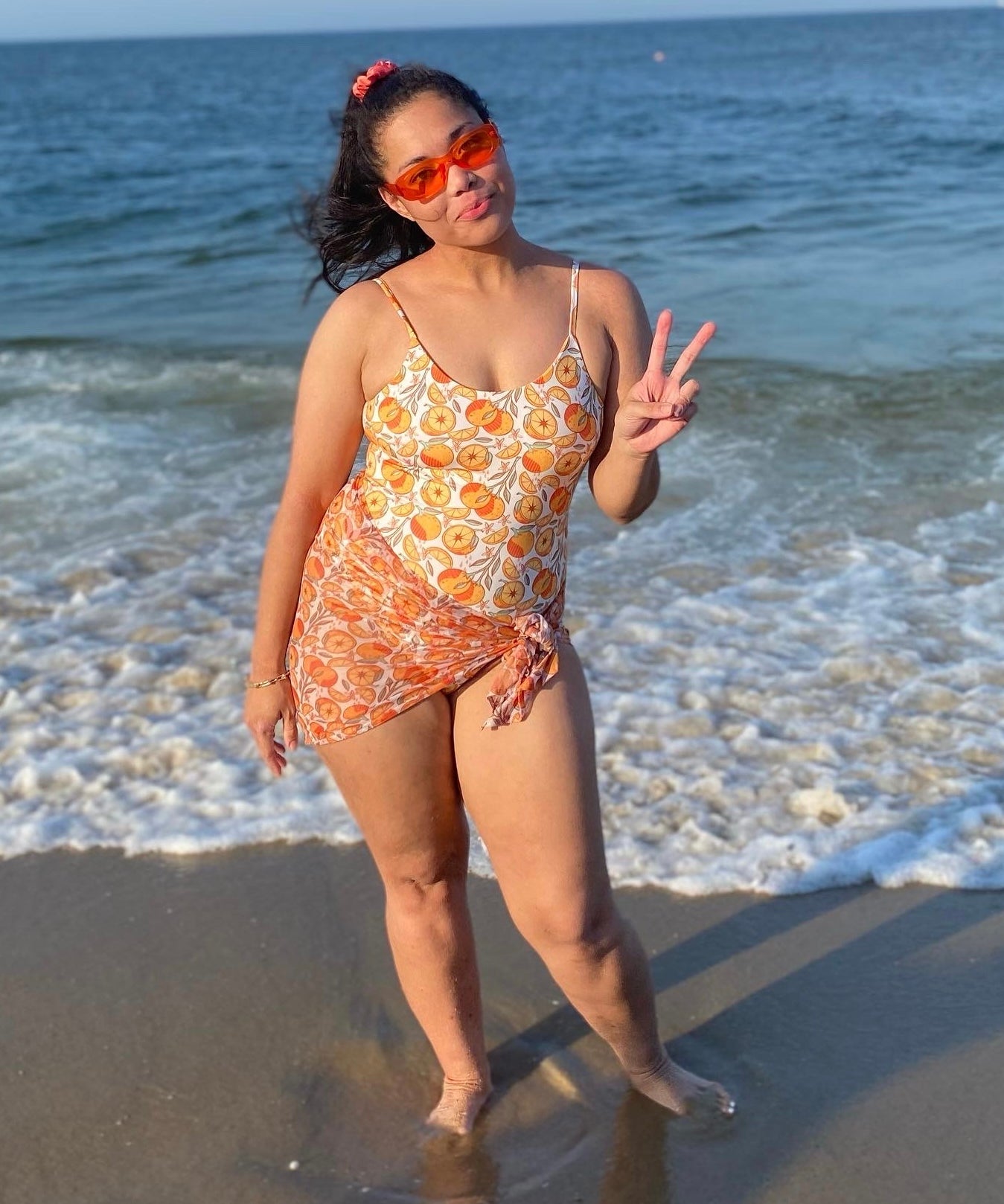 woman at the beach in reversible orange print bikini with matching sarong
