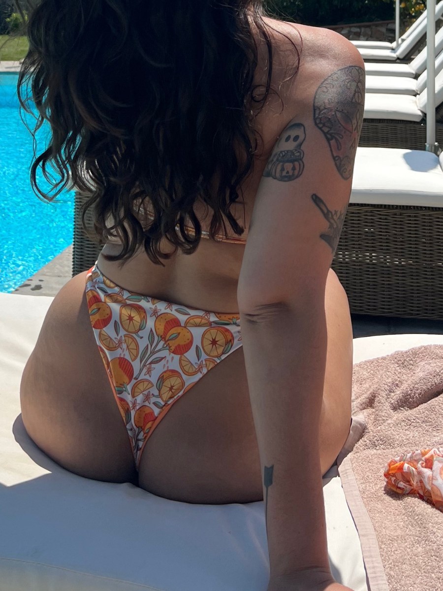close up on backside of woman wearing a reversible orange / orange print high hip thong bikini bottoms