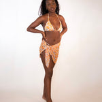 woman in orange print triangle bikini top and matching orange print sarong