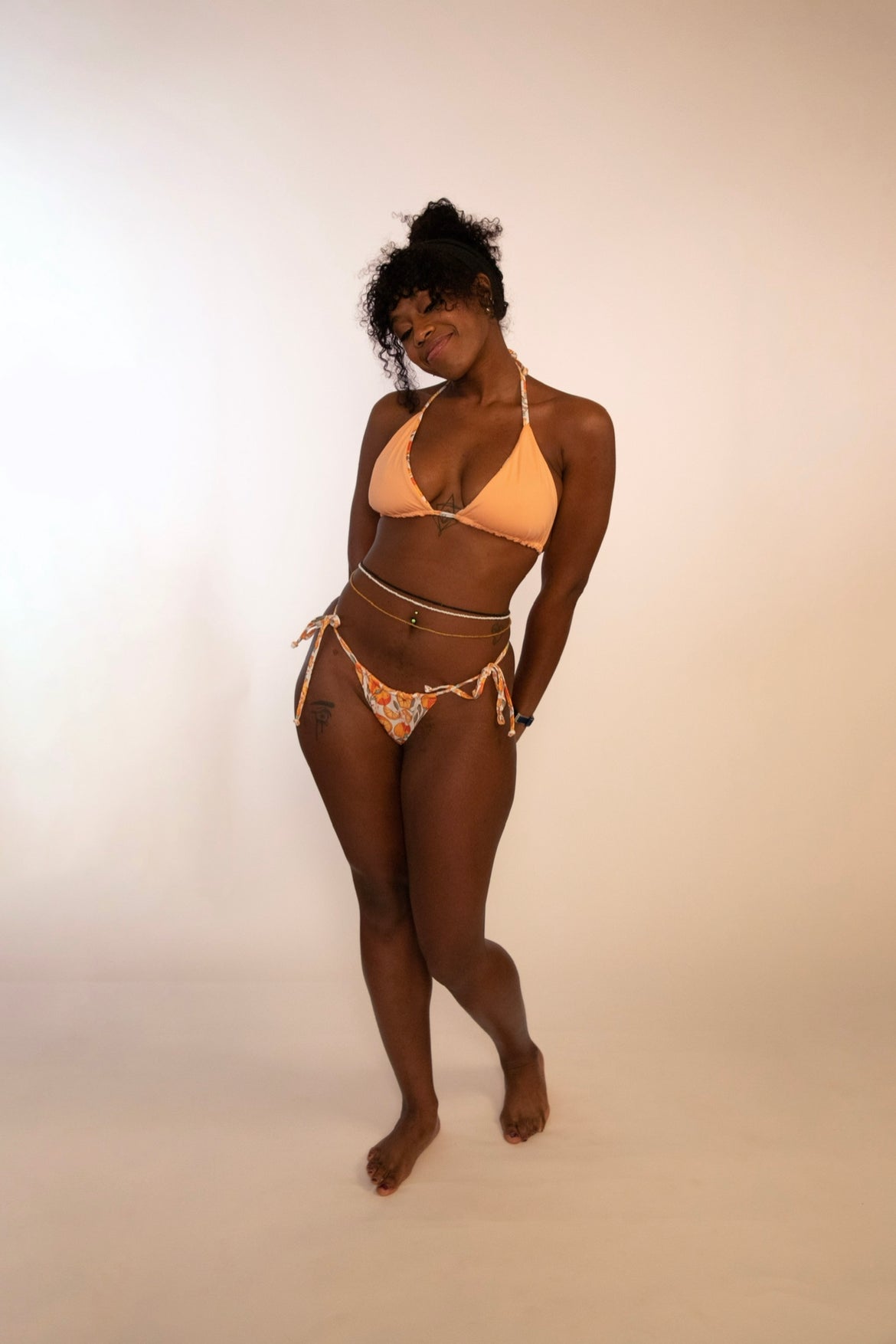 woman in reversed orange print triangle bikini top and tie thong bikini bottom