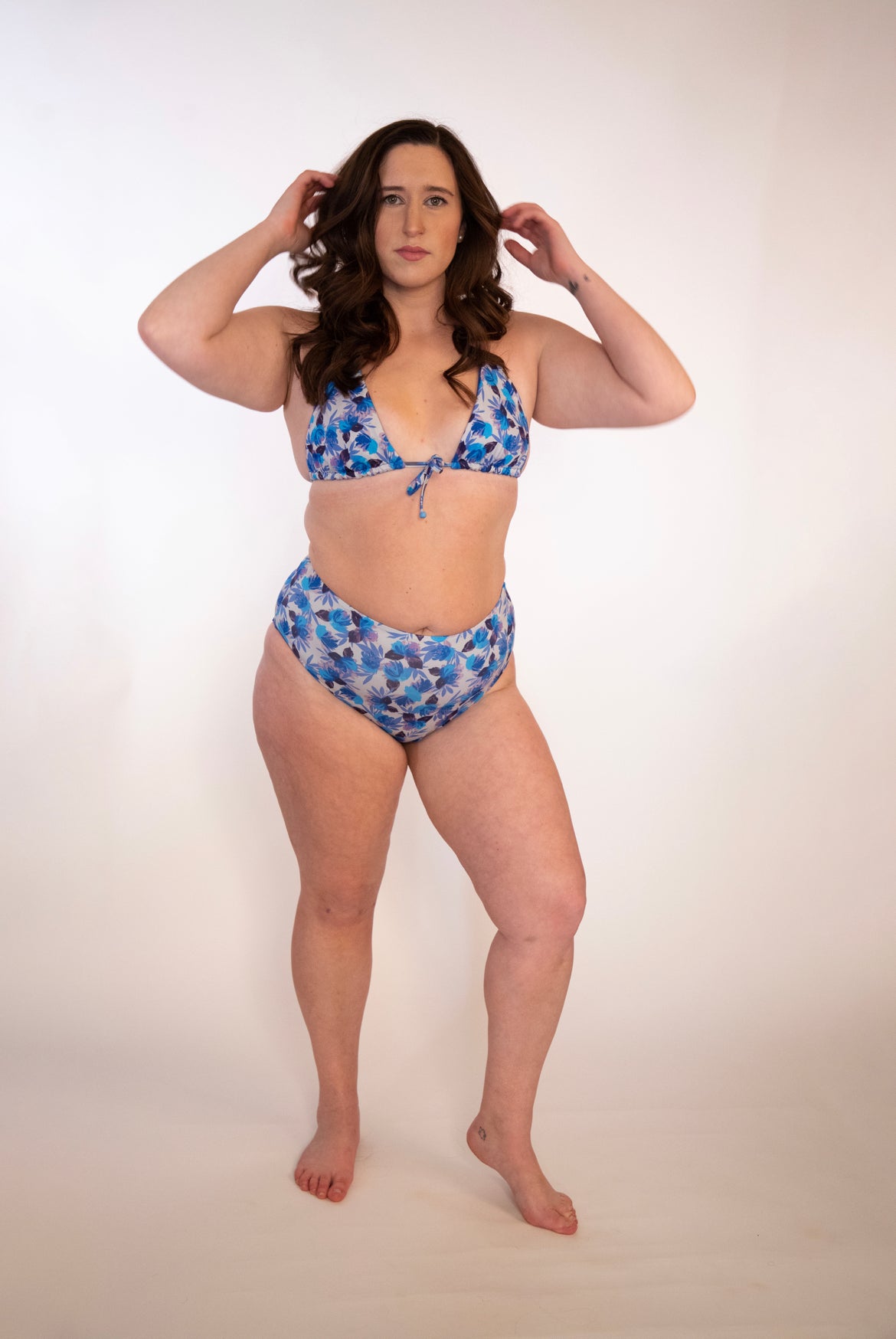 girl in blue floral triangle bikini top tied in front with high waisted blue floral bikini bottoms