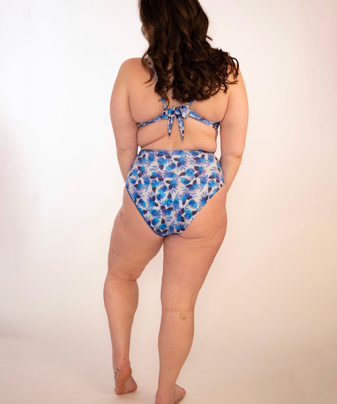woman in blue floral, reversible, high waisted bikini bottoms and matching underwire tie back top from behind