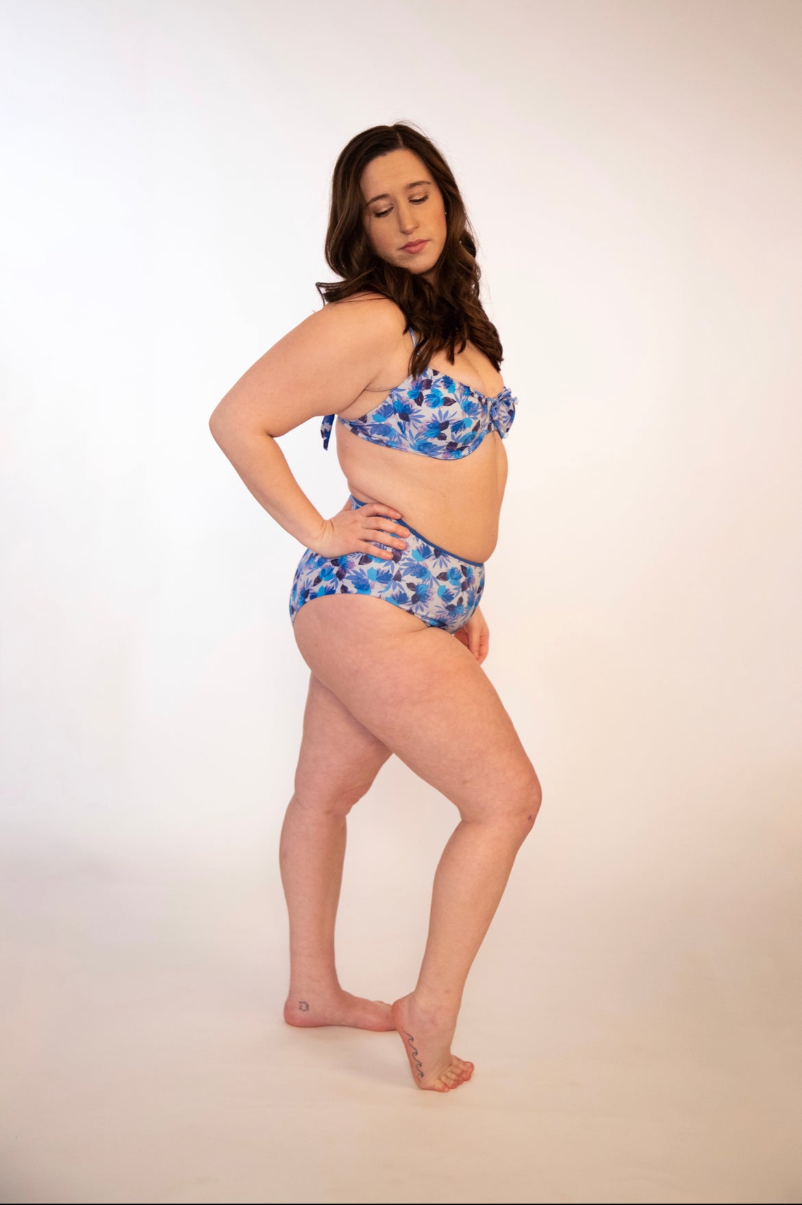 side view of woman in blue floral, reversible, high waisted bikini bottoms and matching underwire top