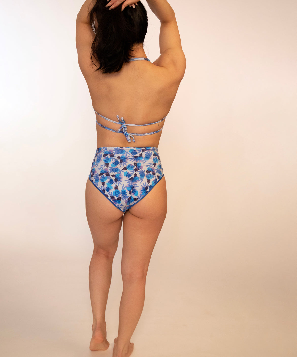 woman in blue floral, reversible, high waisted bikini bottoms and matching triangle top double tied in back