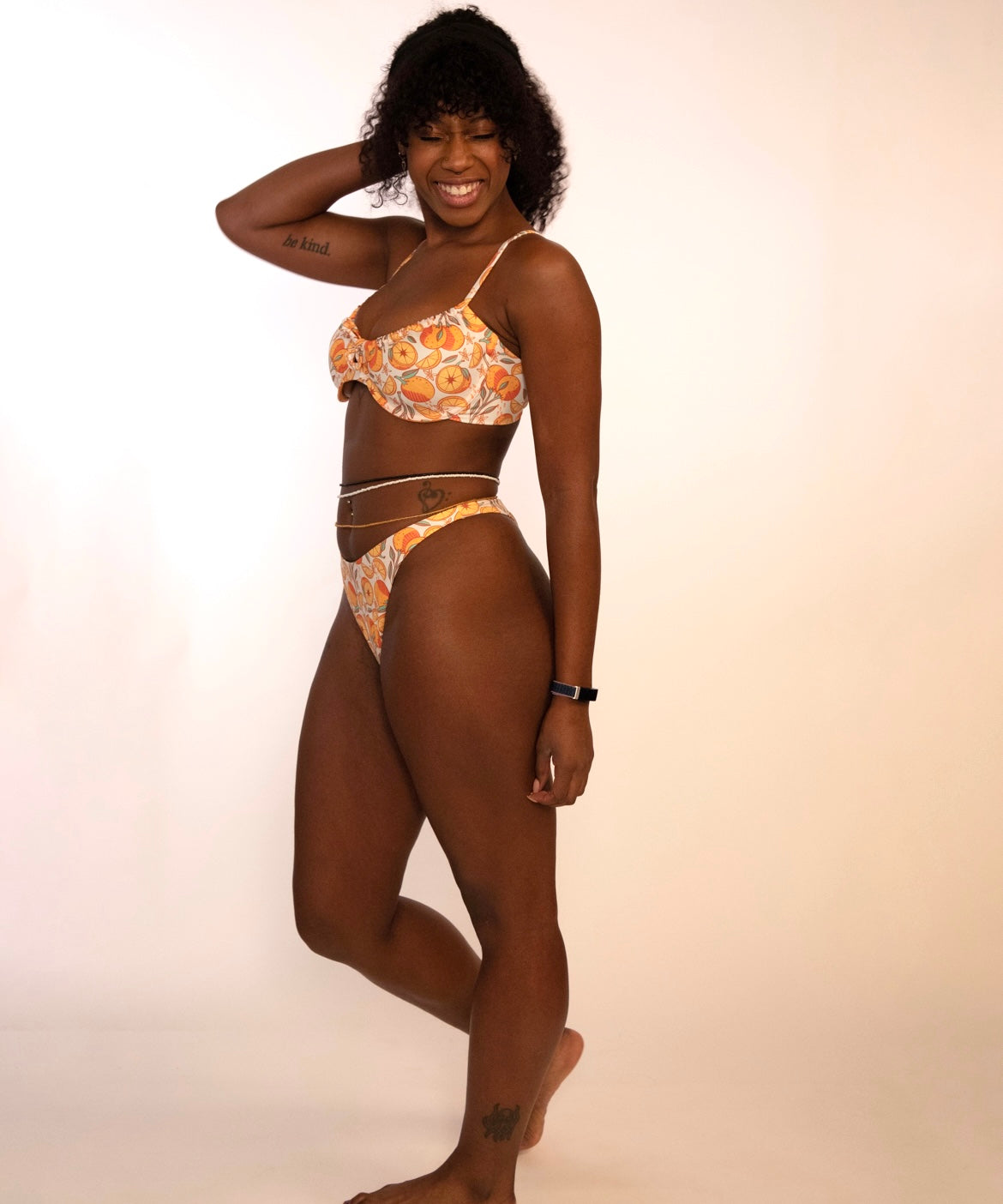 side view of a woman in orange print underwire bikini top and matching high hip thong bottoms