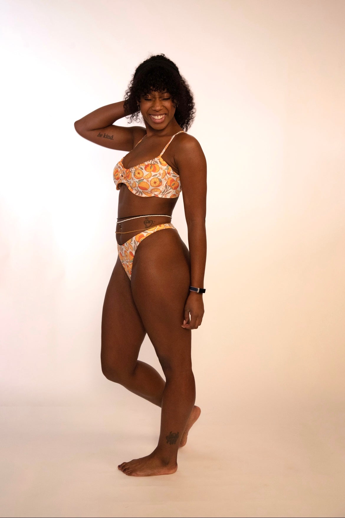 side view of a woman in orange print underwire bikini top and matching high hip thong bottoms