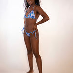 woman in a blue floral triangle bikini top and matching side tie thong bottoms