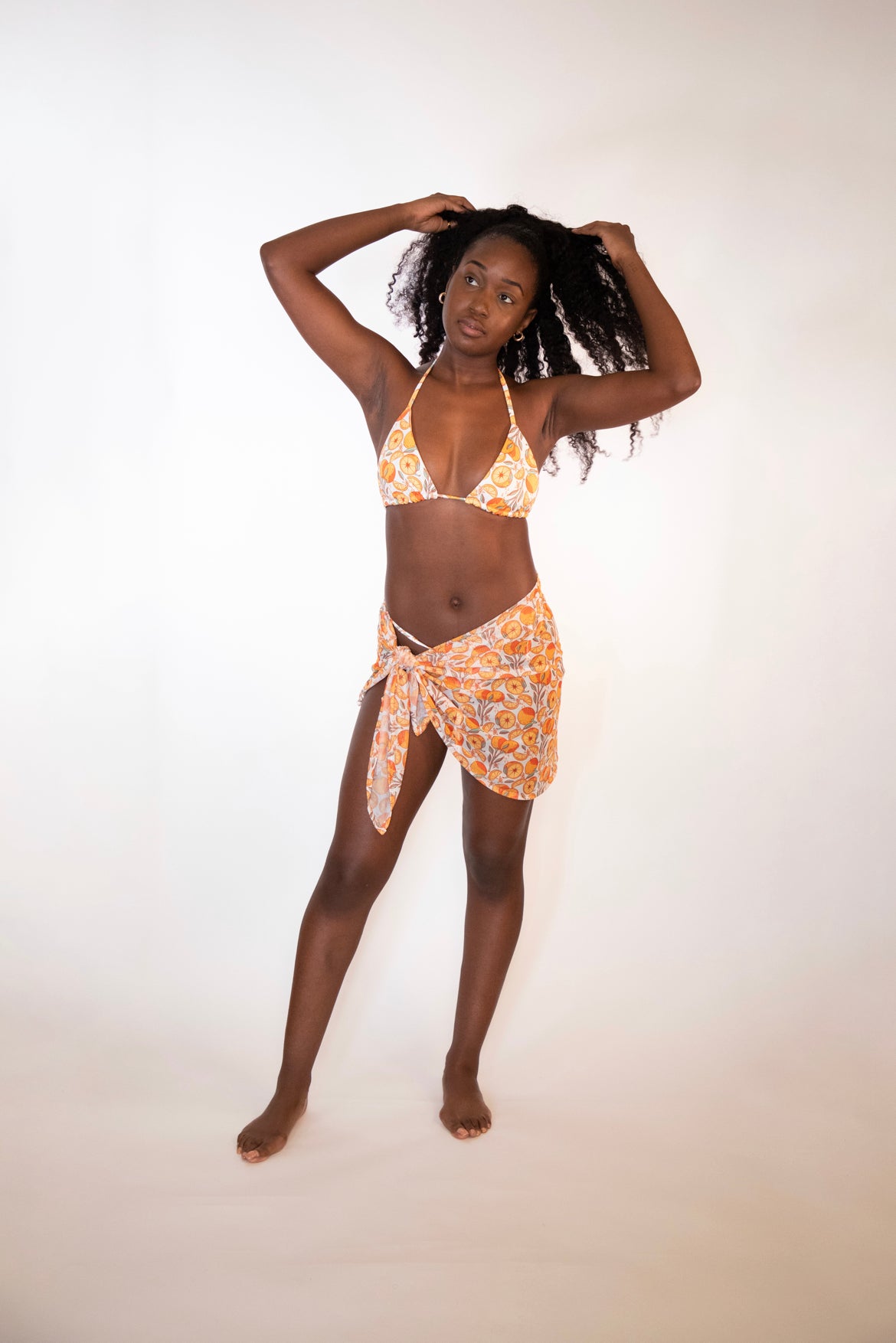 woman in a sheer orange print sarong and matching triangle top