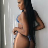 black woman with long braids wearing a reversible blue triangle top and blue floral thong bikini bottoms from behind